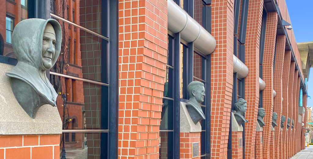 Red brick and glass building with busts of historic figures along the side.